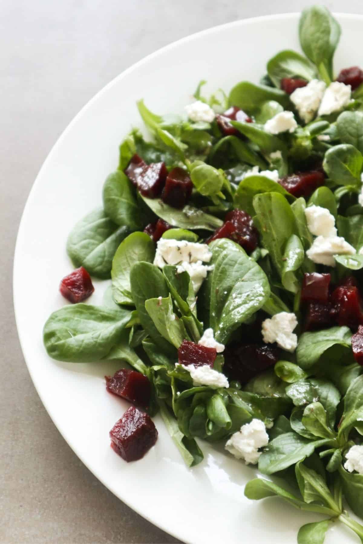 rode bietjes met veldsla en geitenkaas salade op een wit bord.