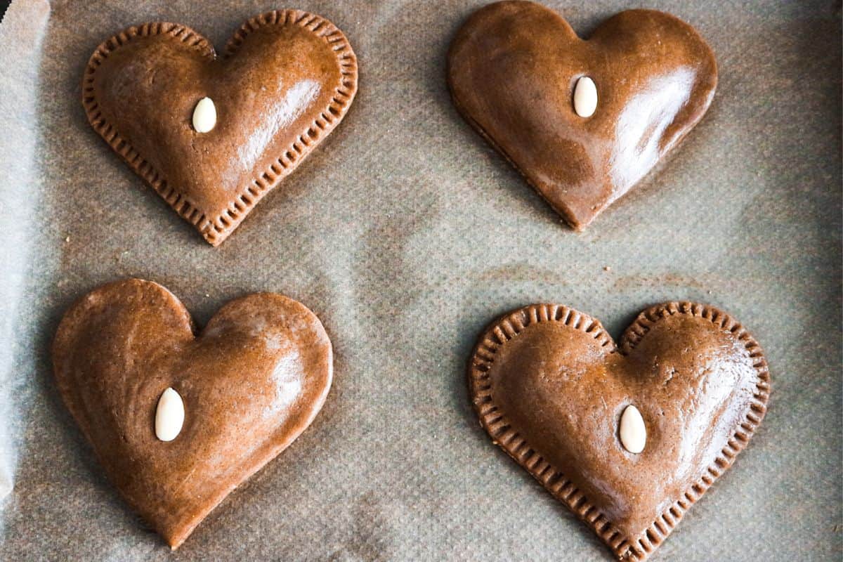 gevulde speculaas harten op een bakplaat gestreken met wat ei