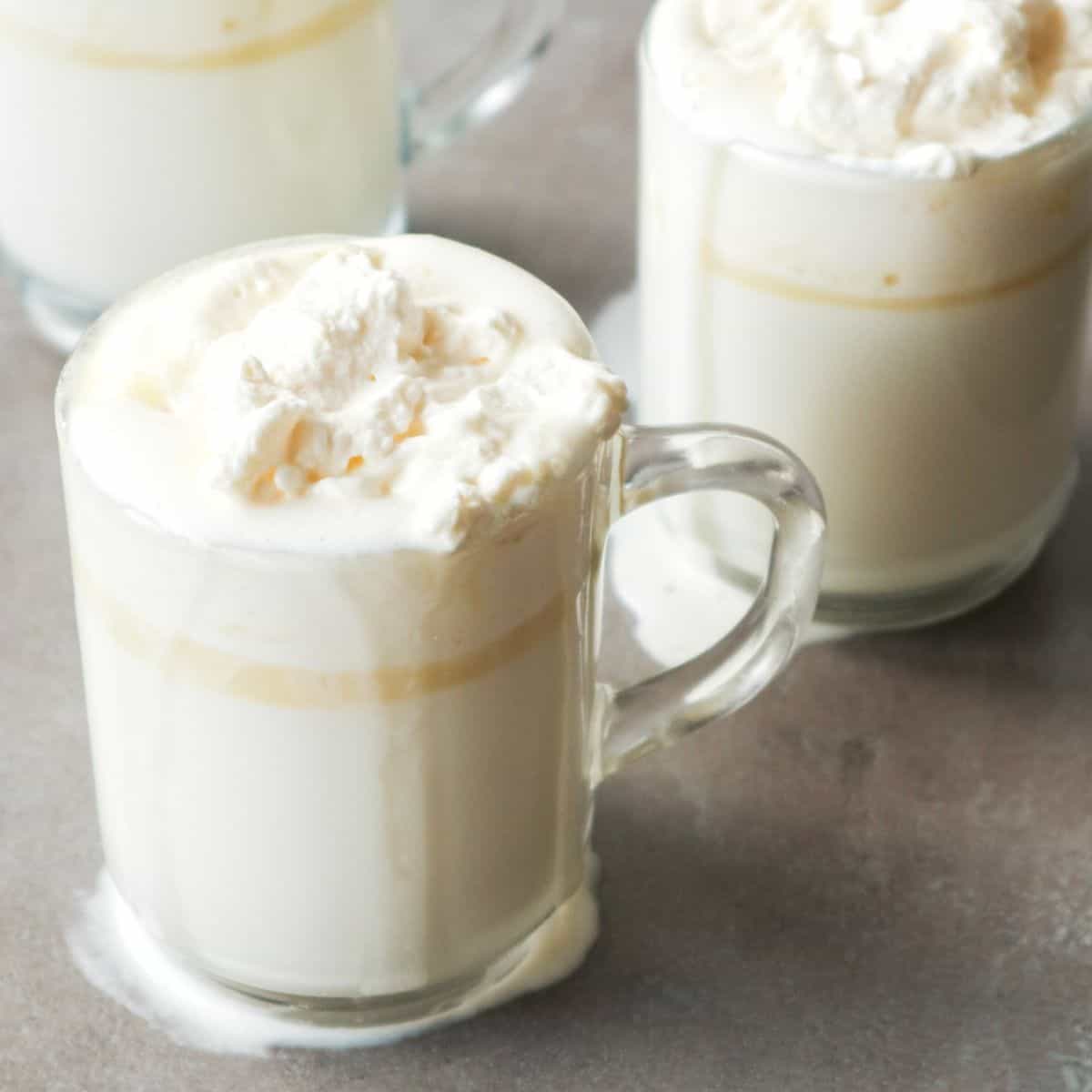 warme witte chocolademelk in theeglazen met slagroom op het aanrecht