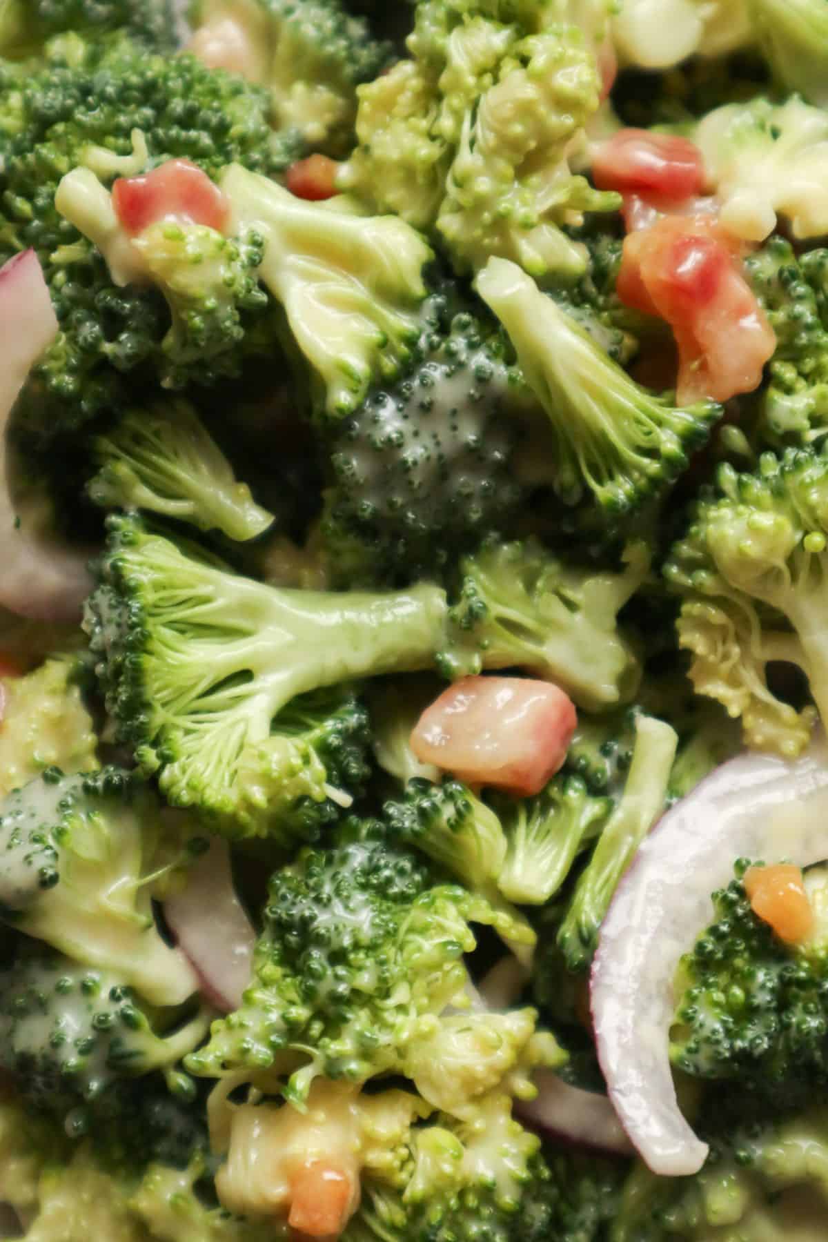 Een close up van een salade met rauwe broccoli, rode ui, gebakken spekjes en mayonnaise