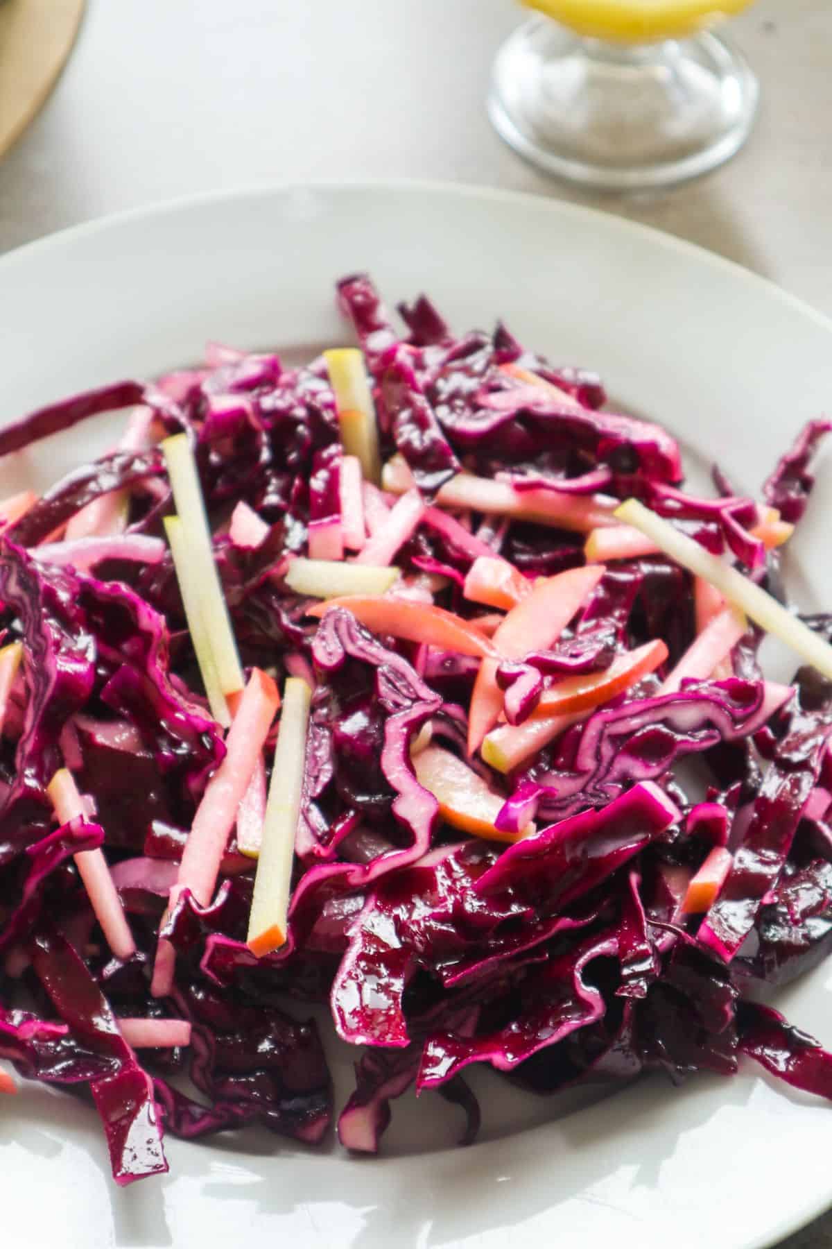 rode koolsalade op een bord met een schaaltje dressing