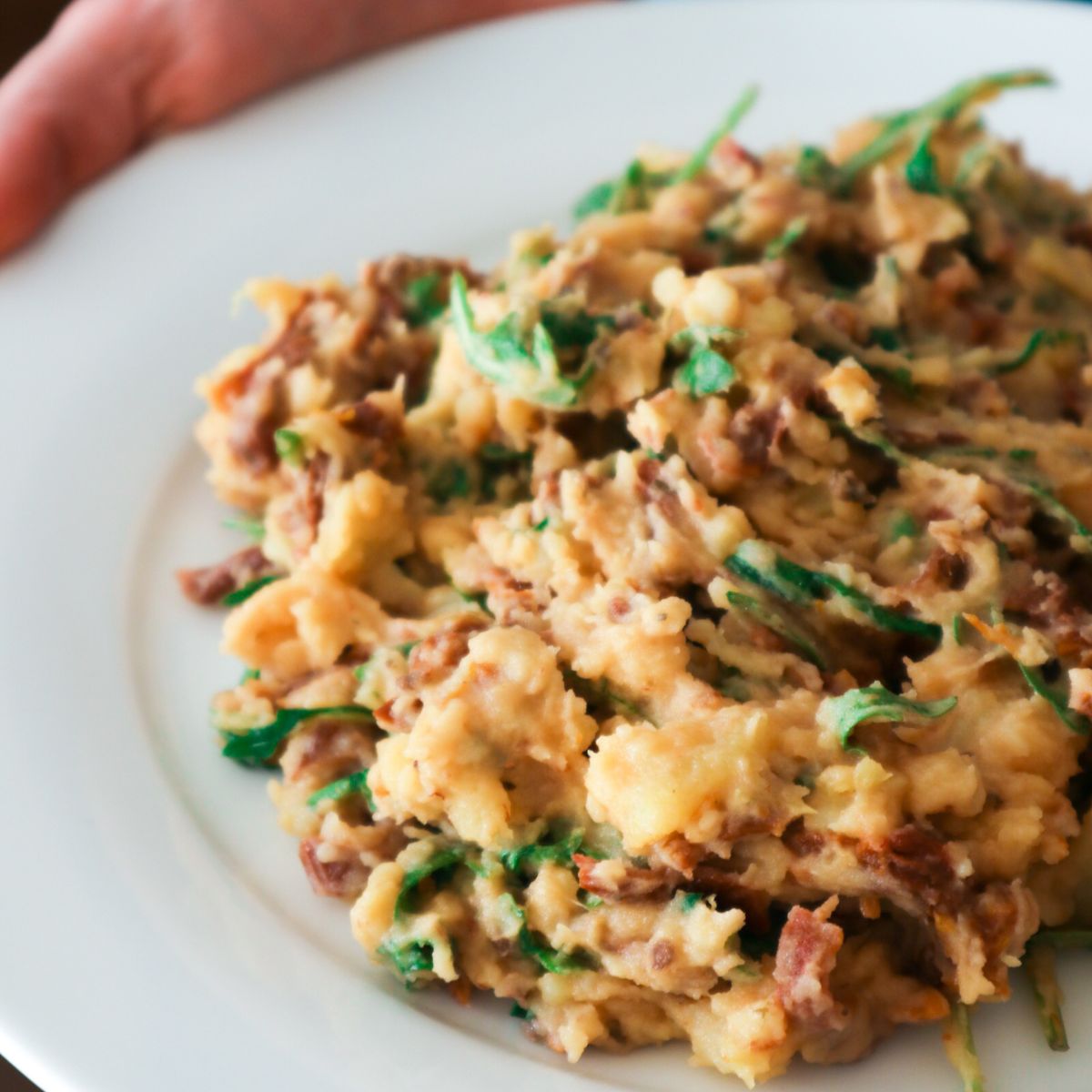 stamppot rucola met zongedroogde tomaatjes op een wit bord