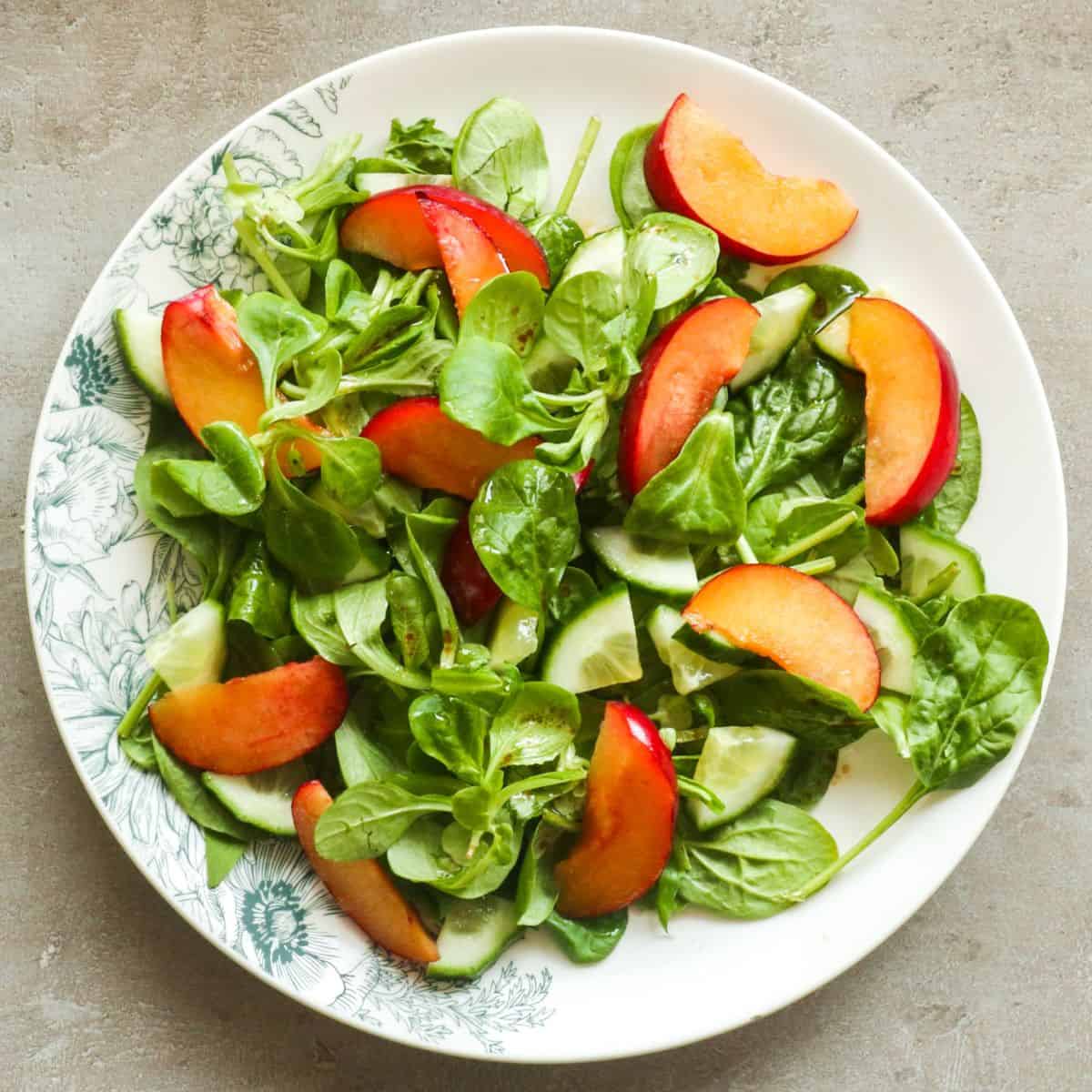 een overhead shot van een salade met fruit op een wit bord