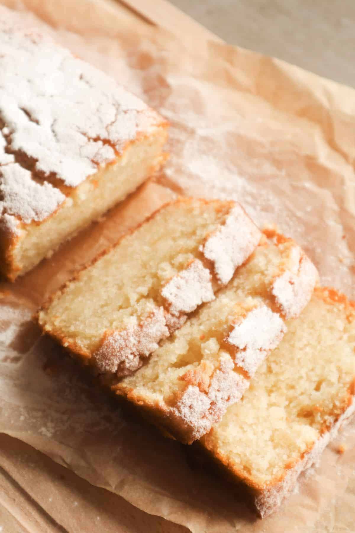 Een vegan cake met gesneden plakjes en poedersuiker op een stuk bakpapier