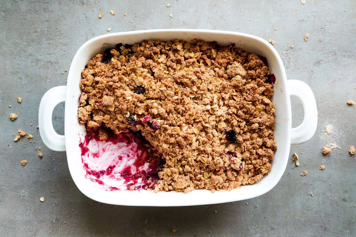 Apple crumble in een schaal samen met blauwe bessen.